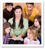 students sitting around a teacher who is reading a book