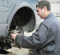 male student fixing a car