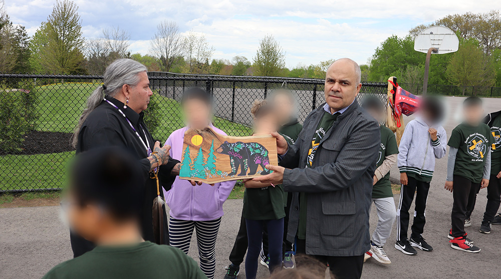 Indigenous community partner Todd Jamieson presents the school with a piece of his original art