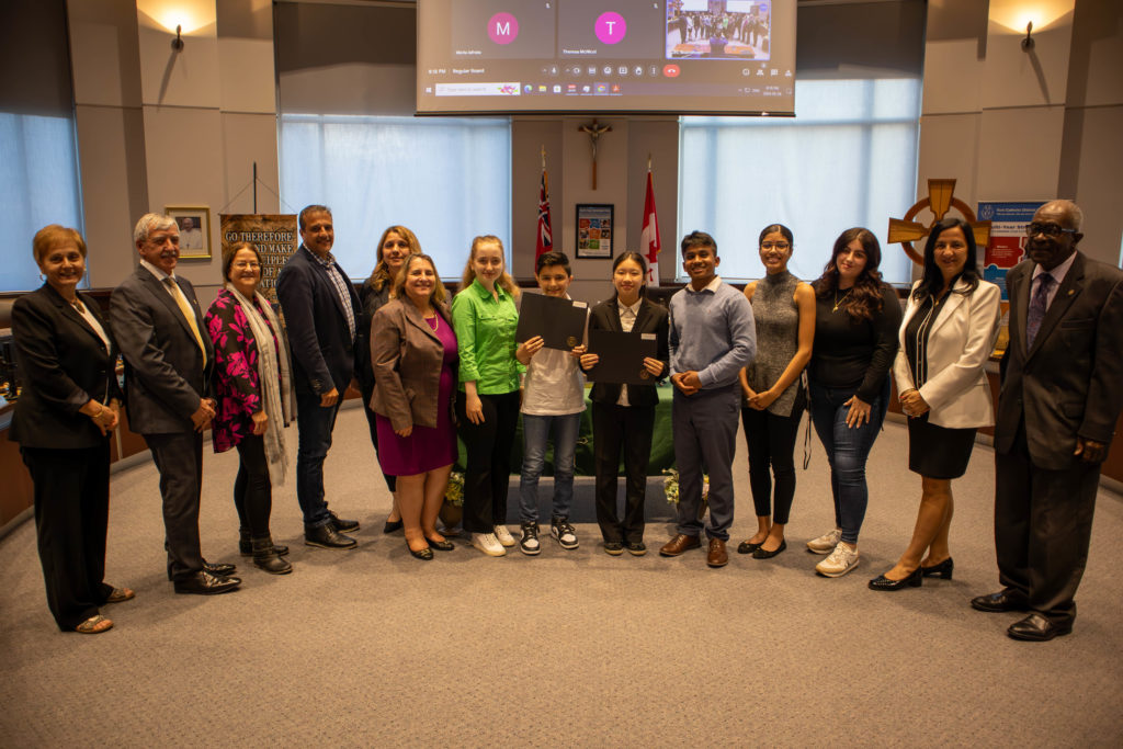 A photo of: Daniel Maggisano of St. Mary CES is the winner of the Junior Division in the Regional Oral Communications Competition. Kaitlyn Ho of St. Charles Garnier CES is the winner of the Intermediate Division. They are in the YCDSB Boardroom pictured with members of the Board of Trustees. 