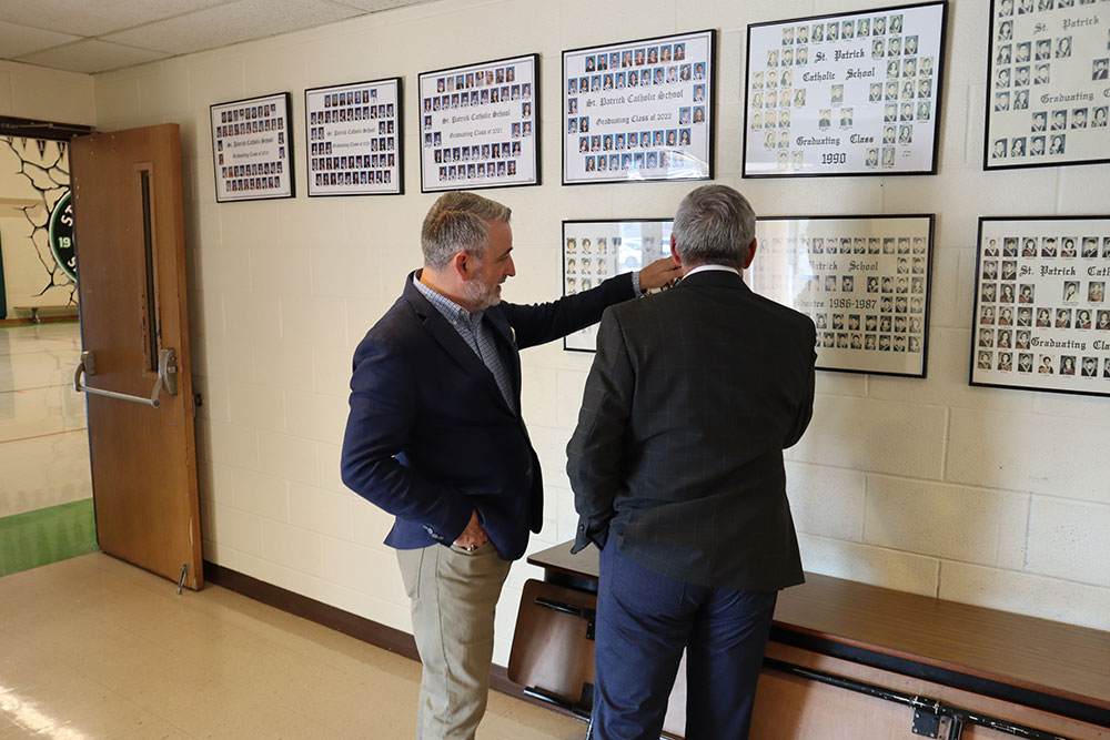 Minister Calandra and Interim Director of Education John De Faveri look at graduation photos in the hallway of St. Patrick CES.