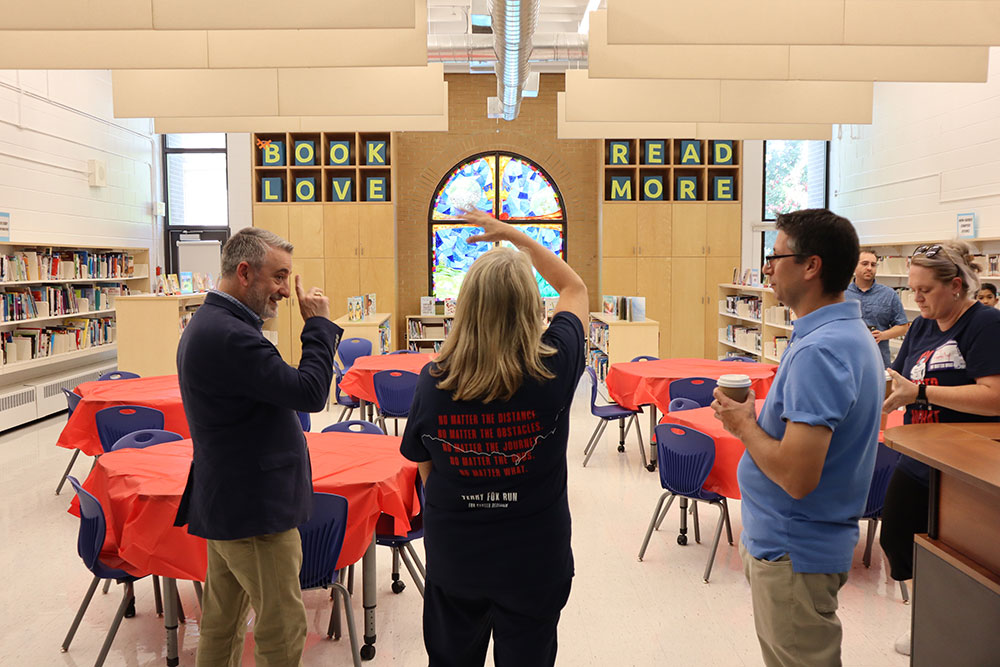 Minister Calandra, Principal Pellegrini and St. Patrick’s staff have an engaging conversation in the library with the words “Book Love. Read More” on the wall in front of them.