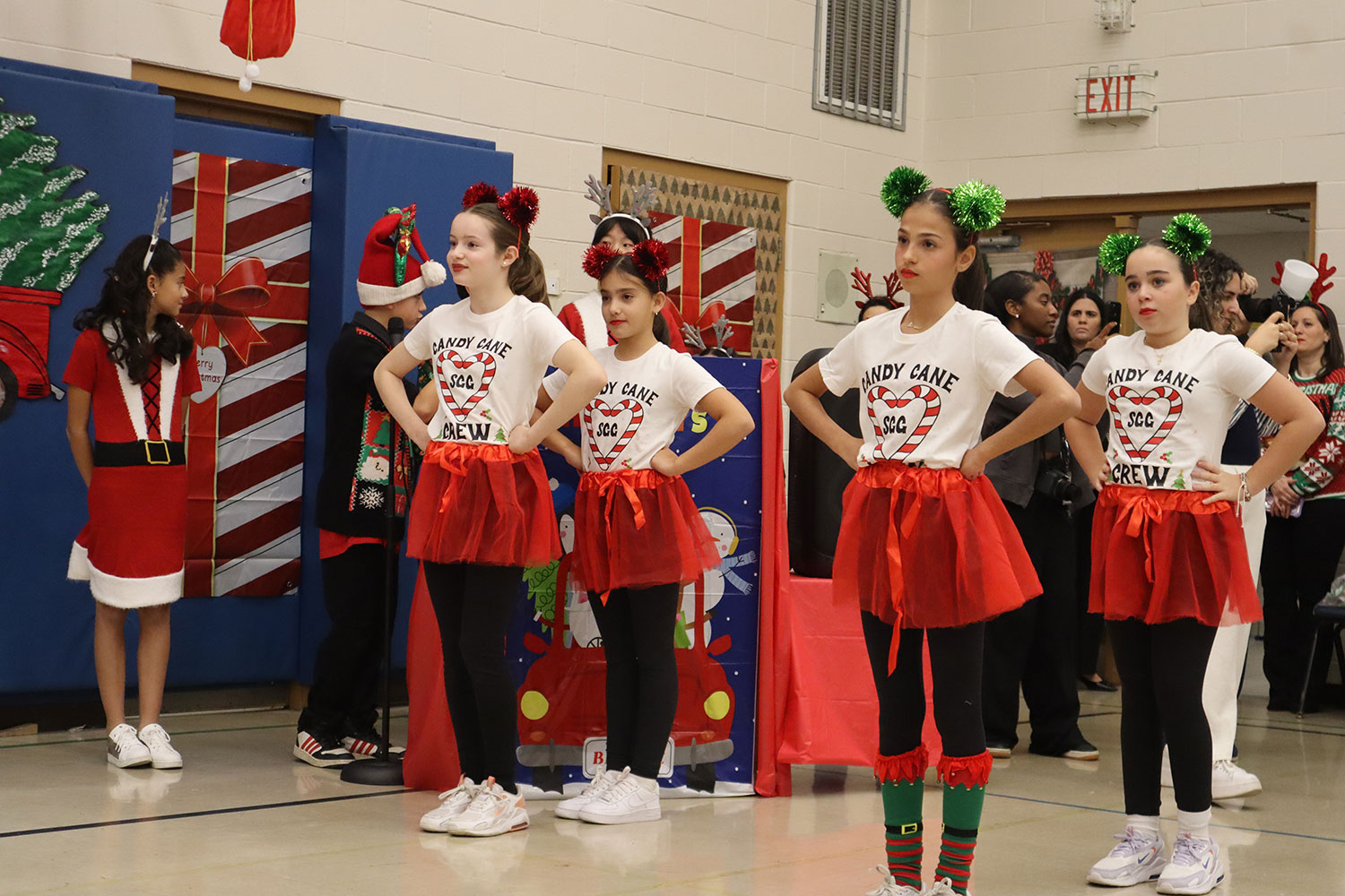 4 girl students in grades 6,7 and 8 dressed in red skirts and white t-shirts with their hands on their hips preparing to start a dance together.